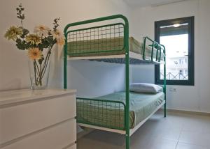 a green bunk bed in a room with a vase of flowers at Torredembarra in Torredembarra