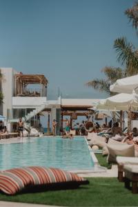 ヘルソニソスにあるGalazio Beach Resort by Estiaの- リゾート内のスイミングプール(長椅子、パラソル付)