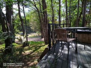 una silla sentada en una cubierta en el bosque en Cabaña con o sin Tinaja Ruta 657, en Coyhaique 2 fotos más