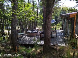 a wooden deck with a hot tub and a tree at Cabaña con Tinaja Privada Ruta 657 in Coihaique