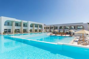 White Hills Resort في شرم الشيخ: مسبح كبير مع كراسي ومظلات بجانب مبنى