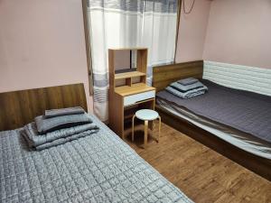 首尔Birdsnest Hostel Hongdae Foreigner only的一间卧室，有两张床、一张书桌和一面镜子