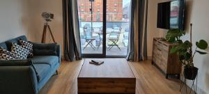 a living room with a couch and a tv and a table at Luxury 1 Bedroom Waterside Apartment in Gloucester Docks in Gloucester