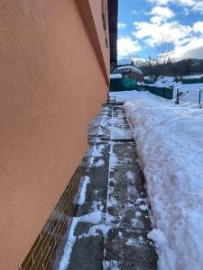 a snow covered sidewalk next to a building at Apartmán Králiky in Králiky