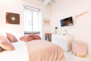 een witte slaapkamer met een bed en een televisie bij Manara 57 Dream Apartment Trastevere in Rome