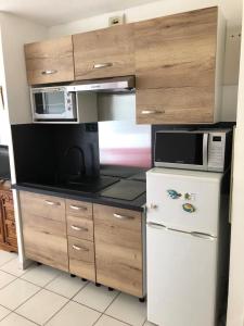 a kitchen with a white refrigerator and a microwave at hippocampe f2 in Fréjus