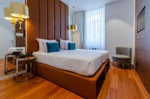 a hotel room with a large bed with blue pillows at The 7 Hotel, Suites, Studios & Apartments in Lisbon