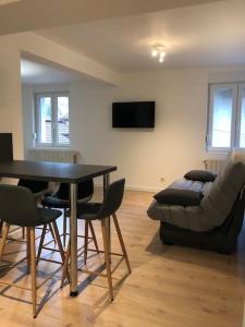ein Wohnzimmer mit einem Tisch, Stühlen und einem Sofa in der Unterkunft Appartement moderne & lumineux 40m2 Centre Luxeuil in Luxeuil-les-Bains