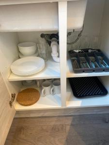 a cupboard filled with plates and other kitchen items at Cosy North London 2 Bed Apartment in Woodside Park- Close to Station and Central London in Totteridge