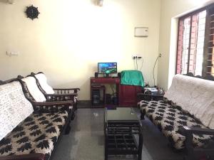 a living room with three couches and a tv at Alapatt Homestay in Alleppey
