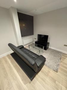 a black leather couch in a living room with a television at Whole apartment in Harrow Town centre in Harrow