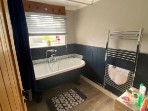 a bathroom with a bath tub and a window at The Cottage at Churchill Farm in Mosterton