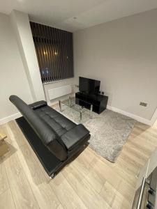 a living room with a black leather couch and a television at Whole apartment in Harrow Town centre in Harrow