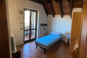 Un dormitorio con una cama azul y una ventana en Casa vacanze Ravascletto en Ravascletto