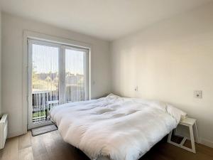 a white bed in a room with a large window at Appartement 'Witte Berg' De Panne in De Panne