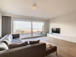a living room with a couch and a large window at Appartement 'Witte Berg' De Panne in De Panne
