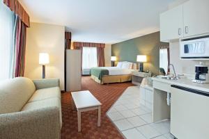 a hotel room with a bed and a living room at Holiday Inn Express Hotel & Suites Corbin, an IHG Hotel in Corbin