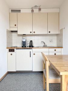 a kitchen with white cabinets and a wooden table at Eva's Seeblick in Krattigen