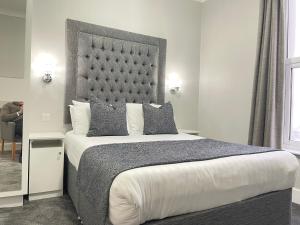 a bedroom with a large bed with a large headboard at Doric Hotel in Blackpool