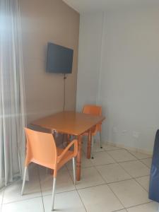 a table with two chairs and a television on a wall at Suíte Thermas Place in Caldas Novas