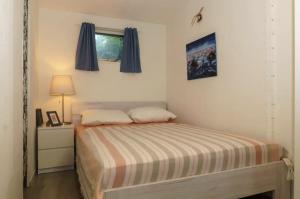 a small bedroom with a bed and a window at Gezellig ingerichte blokhut op een rustig park! in Putten +13 photos