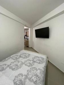 1 dormitorio con 1 cama y TV de pantalla plana en Aparta-hotel Laureles 203, en Medellín