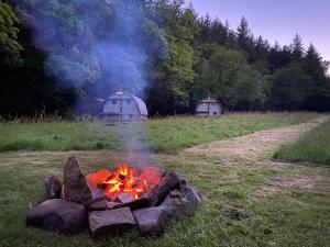 a campfire in a field next to two domes at Exclusive Use Riverside Landpods at Wildish Cornwall in Bodmin