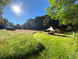 una tienda en un campo con el sol en el cielo en Exclusive Use Riverside Landpods at Wildish Cornwall, en Bodmin
