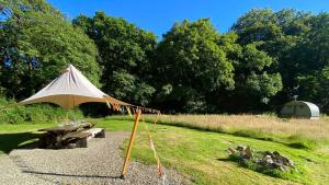 a tent and a picnic table in a field at Exclusive Use Riverside Landpods at Wildish Cornwall in Bodmin