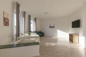 una sala de estar blanca con mesa y sillas en T&K Apartments-Duisburg 4 Zimmer Apartment, en Duisburg