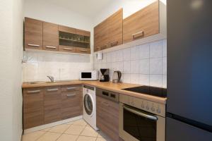 cocina con armarios de madera, fregadero y lavavajillas en T&K Apartments-Duisburg 4 Zimmer Apartment, en Duisburg