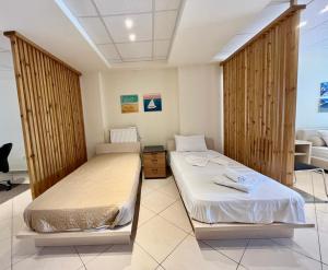 2 letti in una stanza con divisori in legno di Hector Apartment Airport by Airstay a Spata