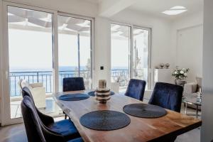a dining room with a table and chairs and windows at Noir Luxury Suite by CorfuEscapes in Corfu