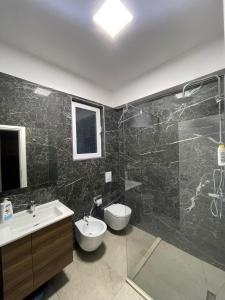 ein Bad mit einem Waschbecken, einem WC und einer Dusche in der Unterkunft Waterfront Apartments in Durrës