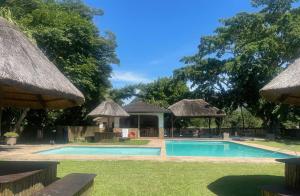 a swimming pool with thatched umbrellas next to a house at Eden Wilds 72 in Port Edward