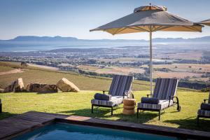 a swimming pool with two chairs and an umbrella at Taaibosch Collection in Stellenbosch