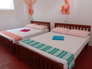two beds sitting next to each other in a room at Happy Stay Holiday Inn in Hikkaduwa