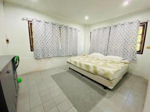 a bedroom with a bed and two windows with curtains at Ma Baan House by the sea in Cha Am Beach