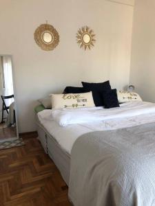 um quarto com uma cama com lençóis brancos e almofadas em Departamento En Vicente Lopez em Vicente López