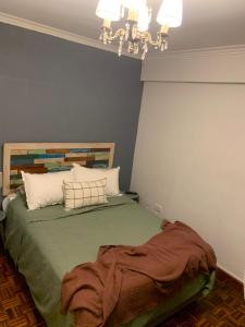1 dormitorio con cama verde y lámpara de araña en Depto confortable en calle Bicentenario en Salta