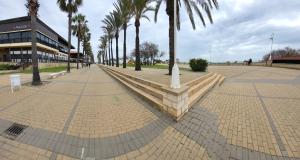 einem Park mit Palmen und einer Bank mit einem Gebäude in der Unterkunft Golf y playa en Islantilla in Huelva