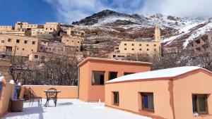 a building with a snow covered mountain in the background at Riad otos views in Imlil