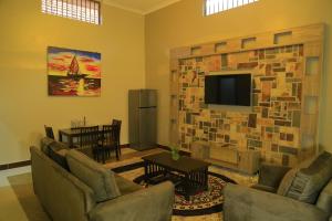 a living room with a stone wall with a flat screen tv at Royal Victoria House Ltd in Kampala