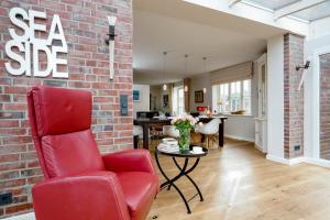 a living room with a red chair and a brick wall at Seaside Lodge Sylt in Westerland