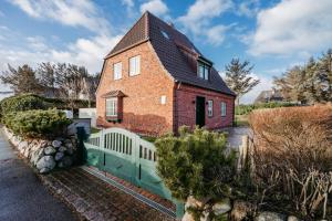 a red brick house with a white fence at Seaside Lodge Sylt in Westerland