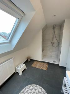 a attic bathroom with a shower and a large window at Wohnungen mit direktem Meerblick in Laboe
