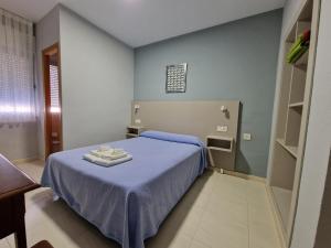 a bedroom with a blue bed with two towels on it at Hostal Soto in La Virgen del Camino