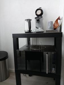 a black shelf with a blender and a clock on it at Studio Slijterij Zandvoort in Zandvoort