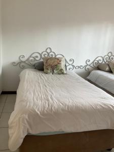 1 dormitorio con cama blanca y cabecero de metal en Vintage Palm II, en Gaborone