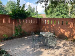 a patio with a table and chairs in front of a brick fence at Vintage Palm II in Gaborone